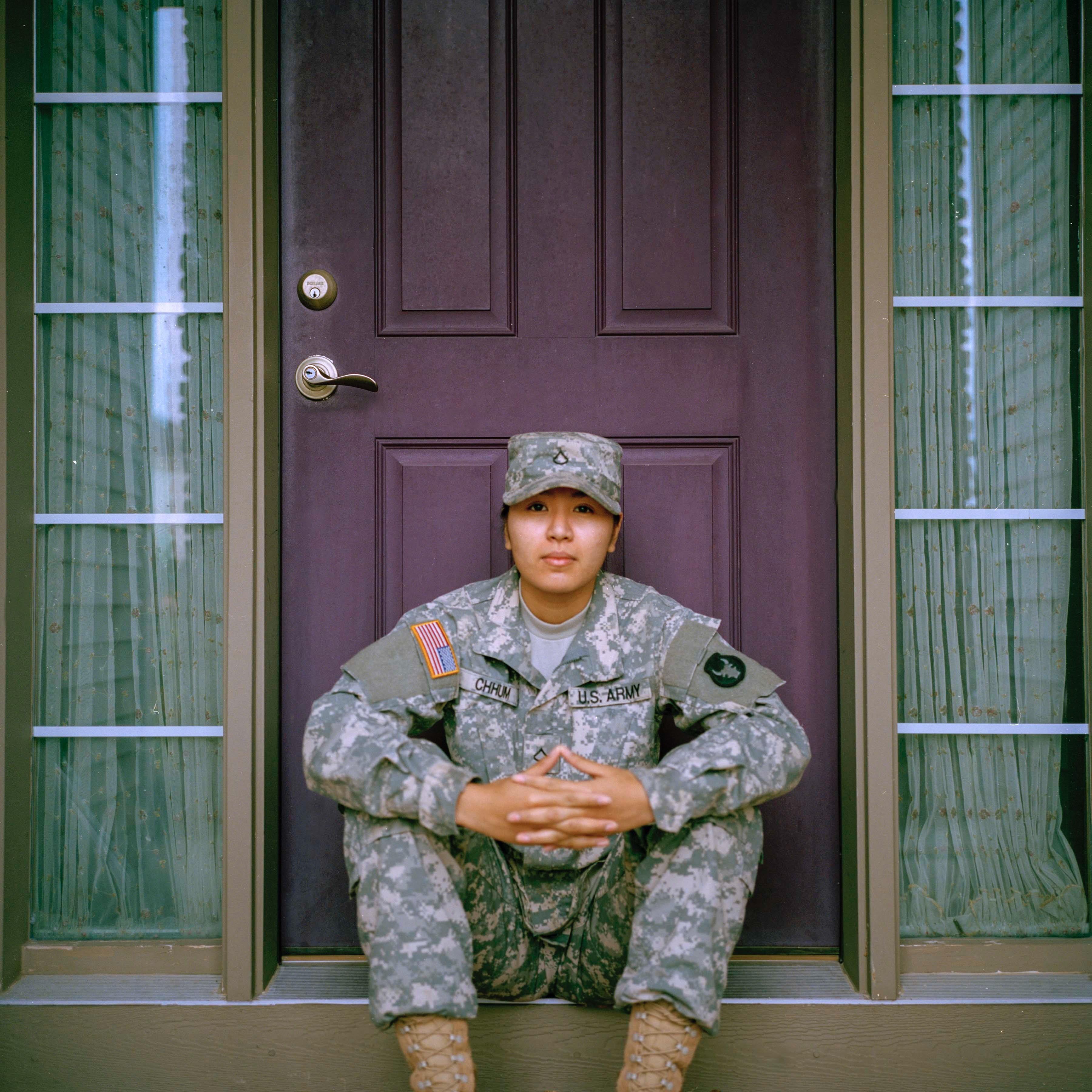 Army woman sitting on step in front of a door